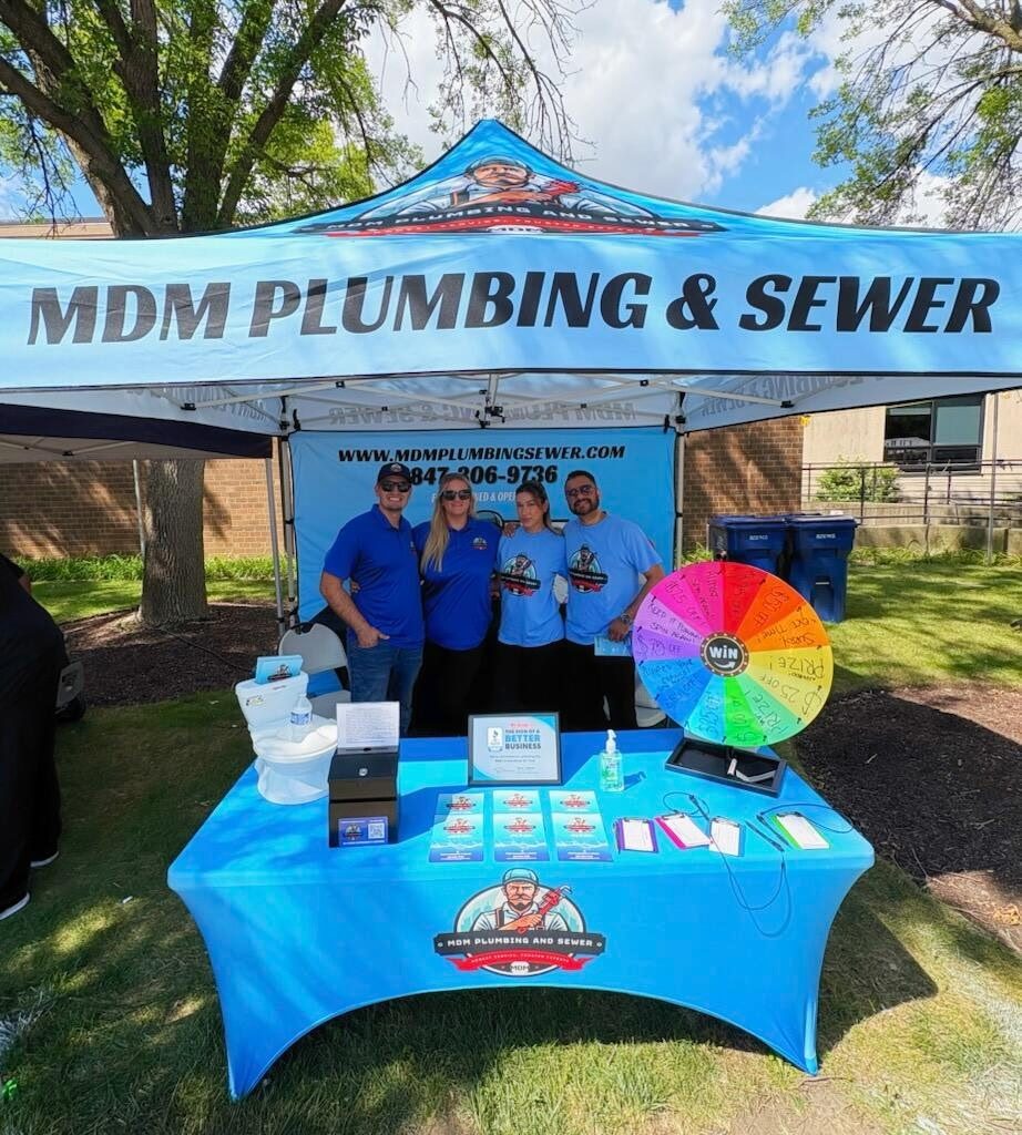 The MDM Plumbing & Sewer team at a Chicagoland community event under their branded tent — family-owned plumbers serving the neighborhood